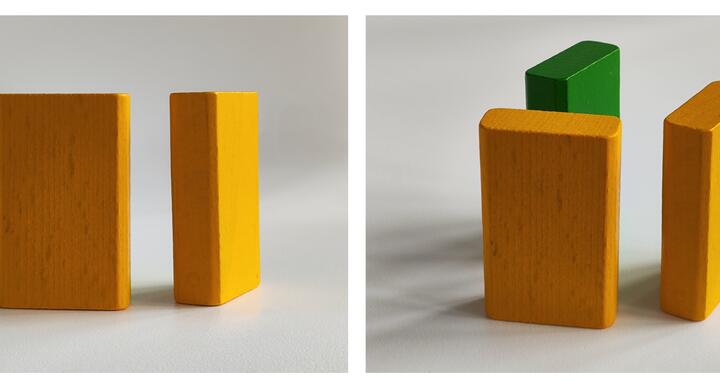 auf der linken Seite stehen zwei gelbe Holzklötzchen ohne Tiefenwirkung, auf der rechten Seite erscheint durch eine andere Perspektive ein drittes Klötzchen in grüner Farbe