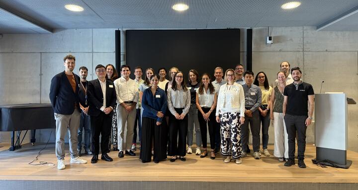 Group photo of attendees smiling on stage at a conference event