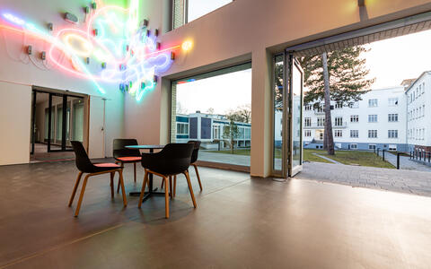 Blick ins Foyer des Käthe-Beutler-Hauses aus Richtung der Rezeption mit einem Teil der Kunst am Bau („Orakel“ des Künstlerduos Borgman | Lenk) links im Bild und Blick in den Innenhof rechts im Bild