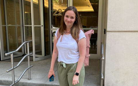 Junge Frau steht vor dem Eingang eines Gebäudes.