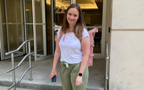 Junge Frau steht vor dem Eingang eines Gebäudes.