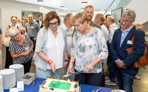 Two women cut an anniversary cake
