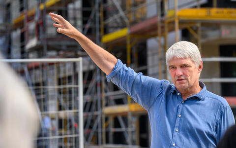 Man gesturing while speaking during a construction site tour.