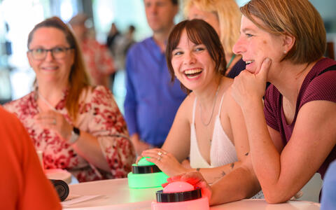 Participants laughing and playing a buzzer-based quiz game.