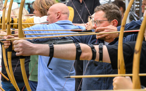 Group of people aiming bows in an archery activity.