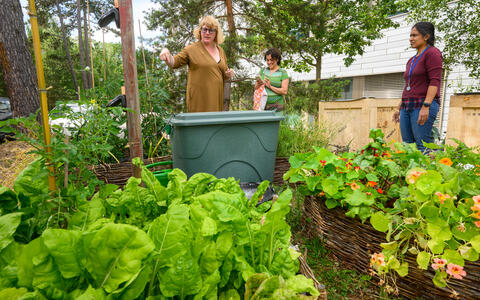 Women giving a garden tour in a lush, raised-bed vegetable garden.