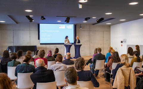 two woman on stage in a lecture hall