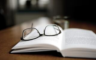 Eine Brille liegt auf einem aufgeschlagenen Buch