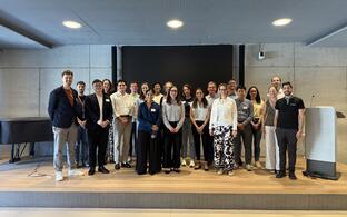 Gruppenfoto von lächelnden Teilnehmern auf der Bühne einer Konferenzveranstaltung