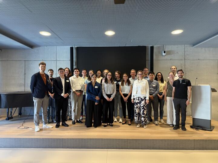 Gruppenfoto von lächelnden Teilnehmern auf der Bühne einer Konferenzveranstaltung