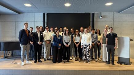 Group photo of attendees smiling on stage at a conference event
